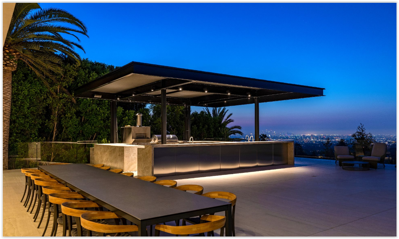 Covered outdoor kitchen and dining pavilion overlooking the Los Angeles skyline at a modern private estate rental.