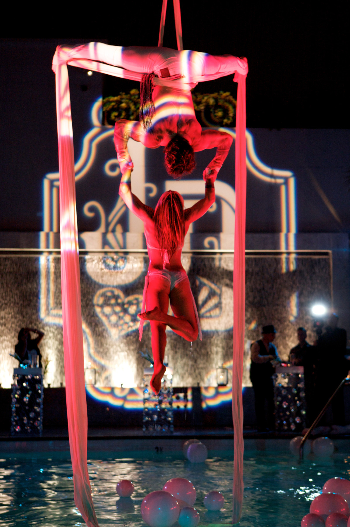 Professional acrobatic performers entertaining guests during a luxury rooftop event with elegant cabanas, custom lighting, and premium event production by Gianna & Company.