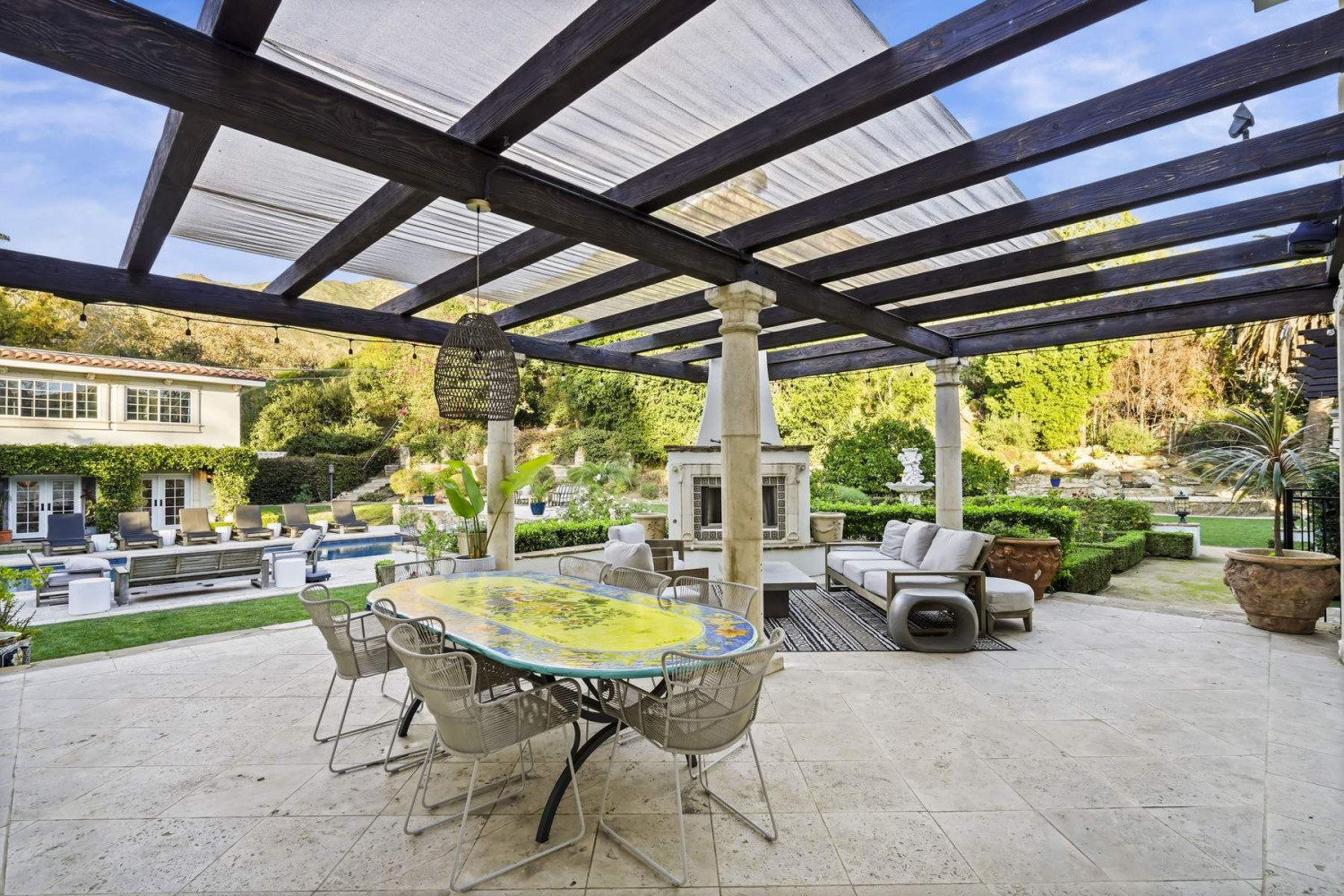 Outdoor dining terrace surrounded by mature landscaping at a private Malibu estate.
