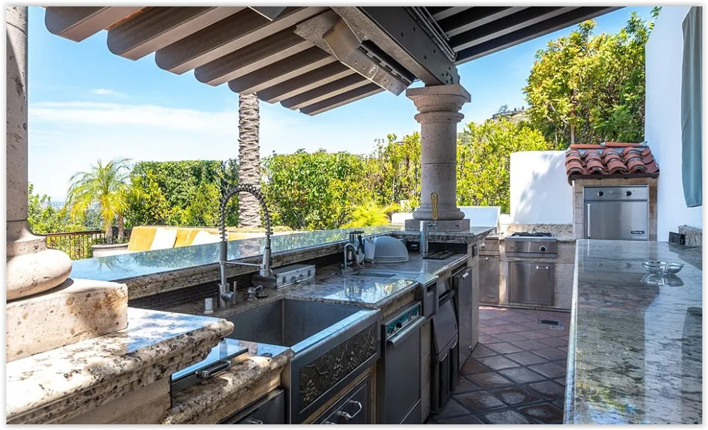 Covered outdoor gourmet kitchen with built-in barbecue and granite countertops for al fresco entertaining.