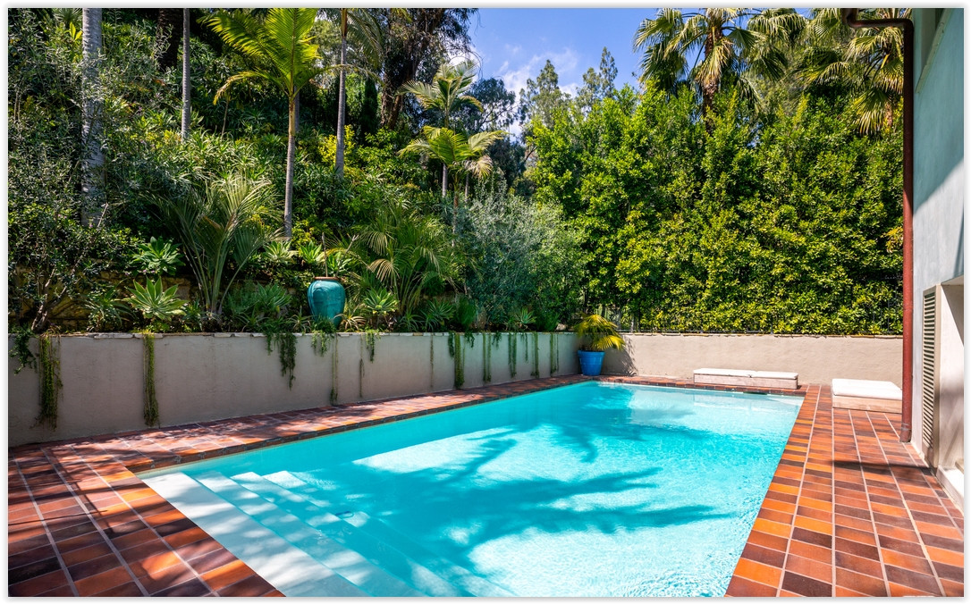 Swimming pool framed by lush tropical landscaping, creating a peaceful outdoor retreat at this Los Feliz estate.