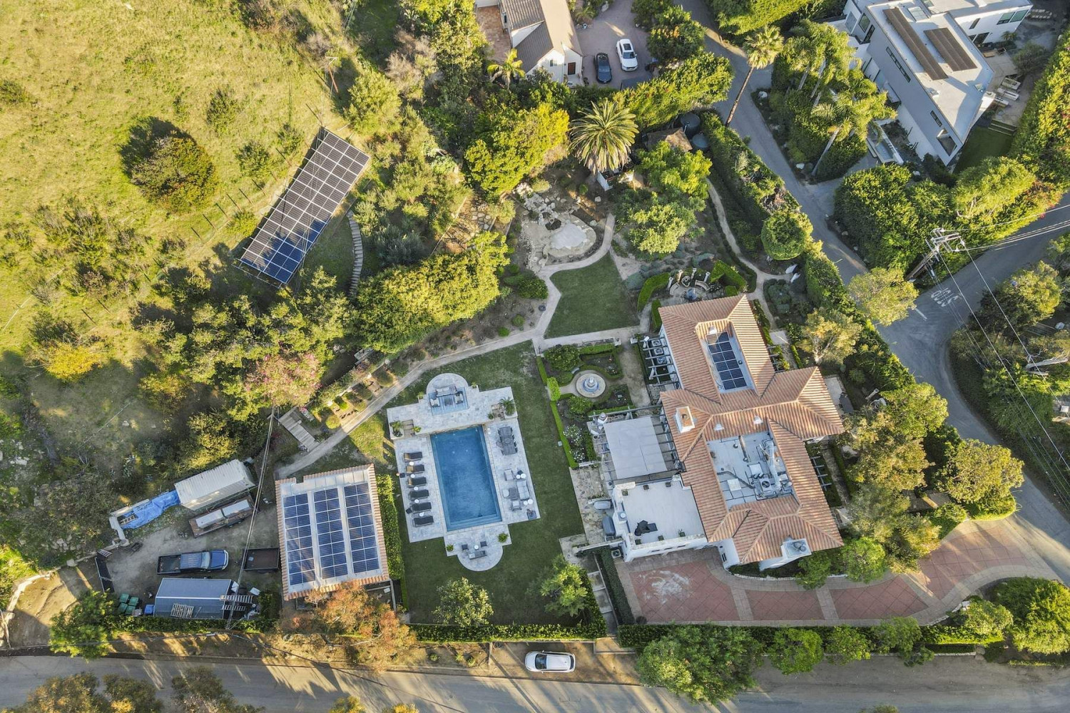 Aerial view of a private Malibu estate featuring landscaped grounds, a resort-style pool, guest house, and surrounding canyon setting.