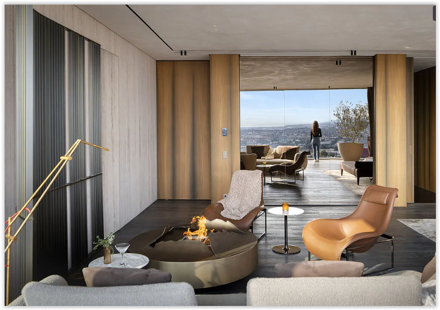Modern living room with designer furnishings, a sculptural fire feature, and seamless indoor-outdoor living overlooking Los Angeles.