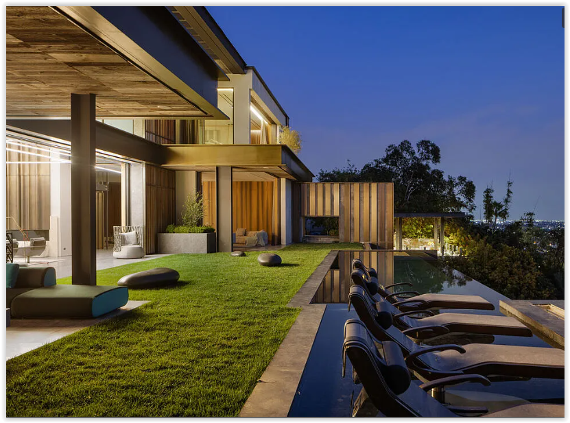 Infinity-edge pool with in-water lounge chairs overlooking panoramic city views from a modern Los Angeles estate.