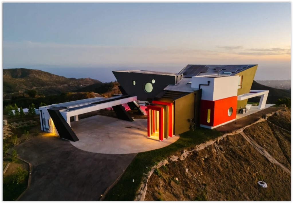 Distinctive contemporary Malibu retreat with dramatic angular architecture, panoramic hillside views, and illuminated architectural details at sunset.