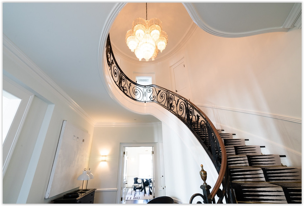 Grand curved staircase with custom iron railing inside a timeless Beverly Hills estate.