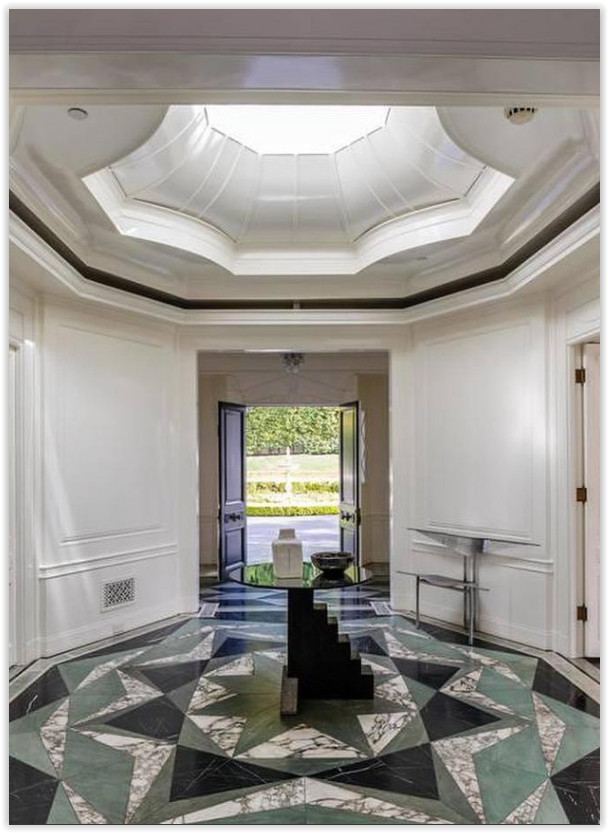 Elegant marble foyer with geometric stone flooring, skylight, and views through the front entry.