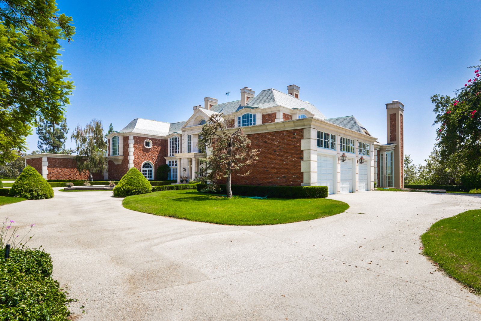 Sweeping driveway leading to a luxury Pasadena estate surrounded by beautifully maintained grounds.