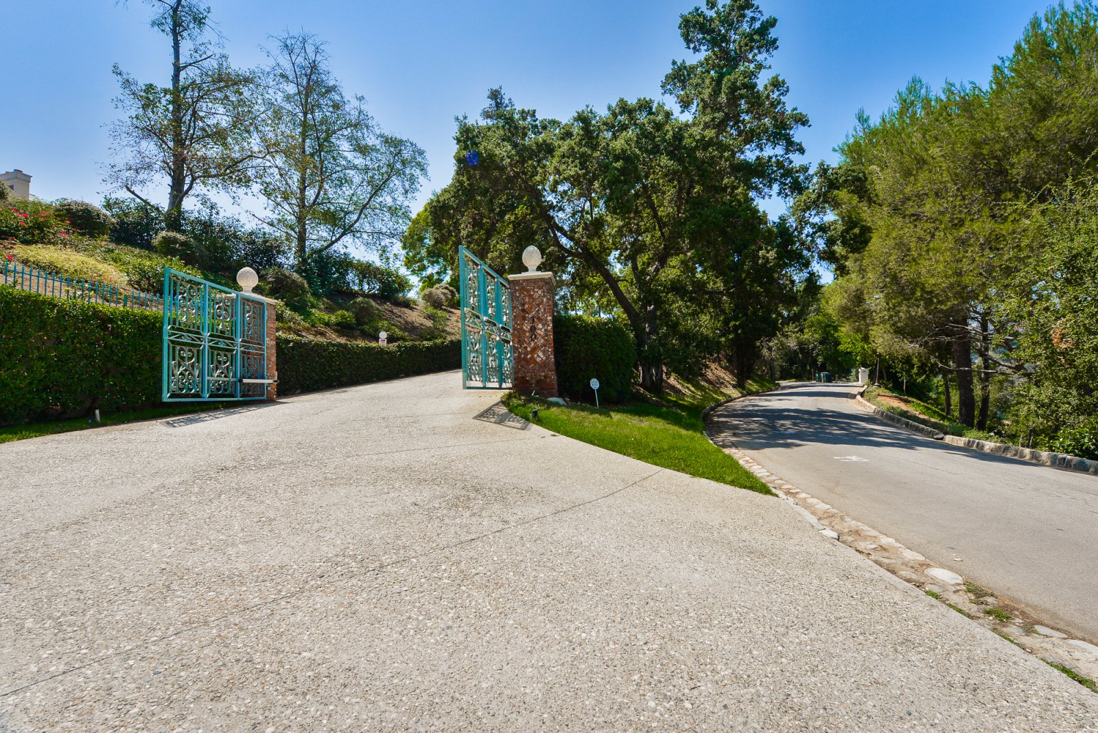 Private gated entrance to an exclusive Pasadena estate with mature trees and a long approach.