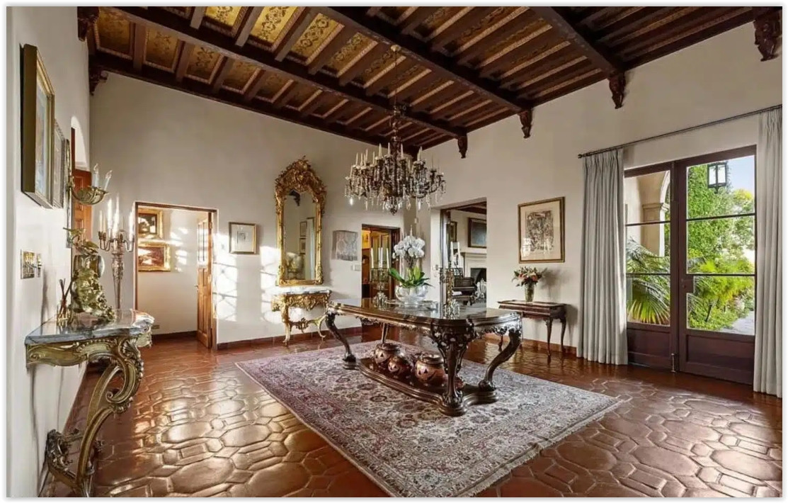 Elegant reception hall with high ceilings, terracotta floors, antique furnishings, and natural light.