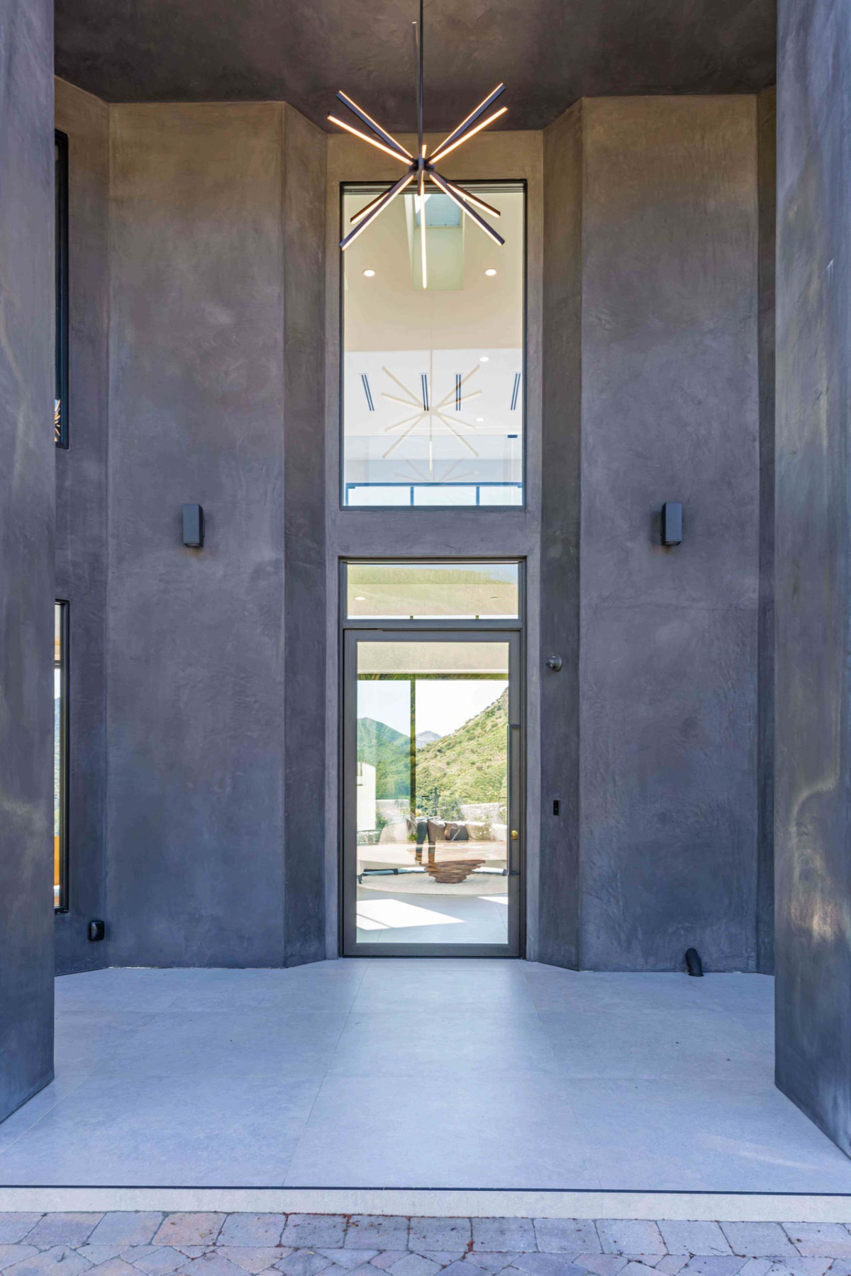 Modern Agoura Hills estate entryway with double-height ceilings, sculptural starburst chandelier, and views into open-concept living spaces.