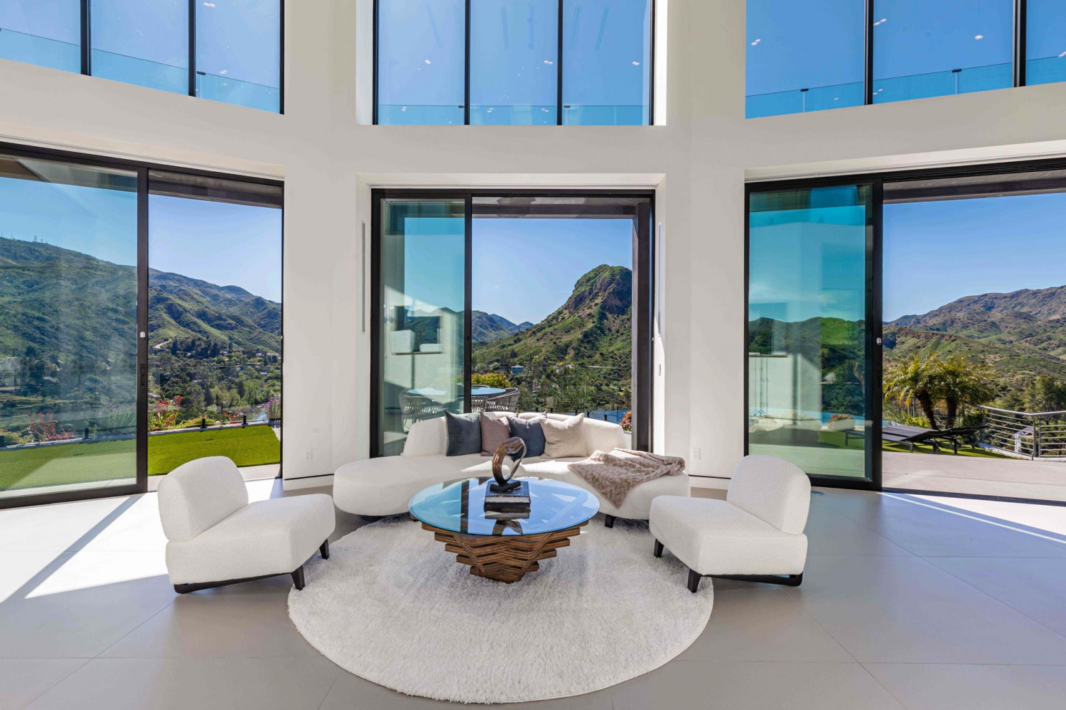 Modern living room with sculptural seating and floor-to-ceiling glass overlooking hillside canyon views in Agoura Hills estate.