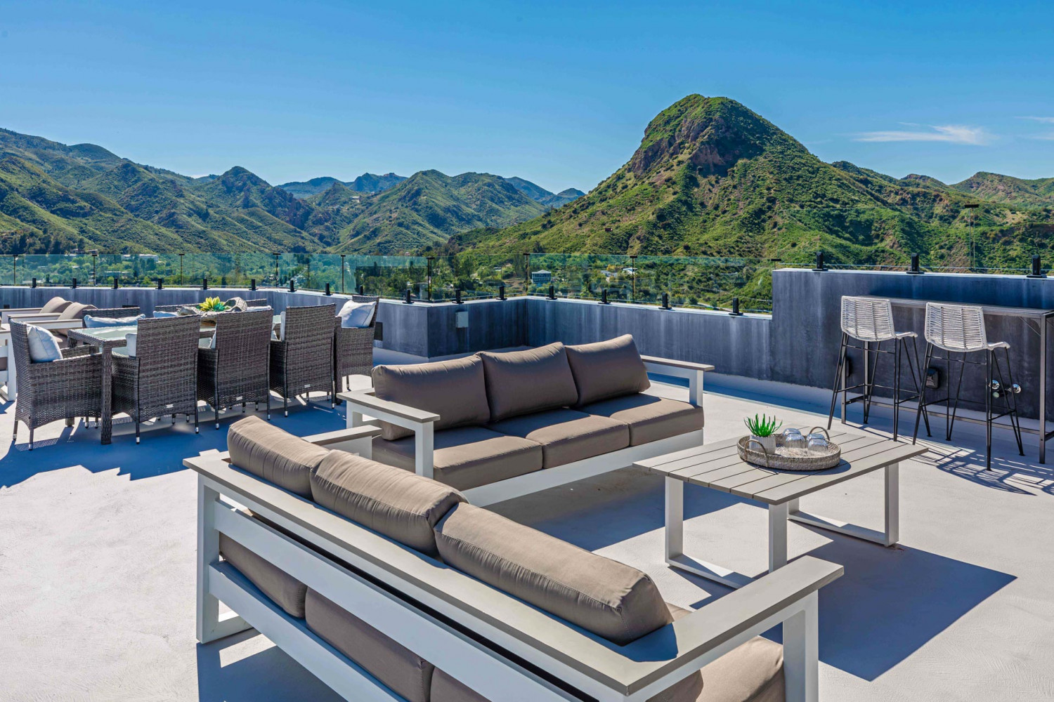 Spacious rooftop terrace at modern Agoura Hills estate featuring outdoor lounge seating, dining area, and panoramic canyon and mountain views in Los Angeles.